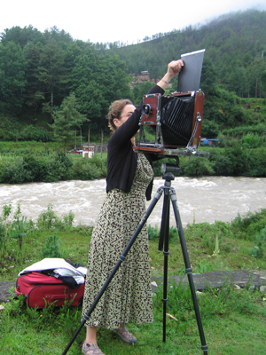 Photographer Regina DeLuise loads a piece of photographic paper into her large format camera in an outdoor location.