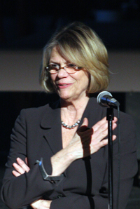 Pamela Ambrose stands before a microphone while addressing an audience