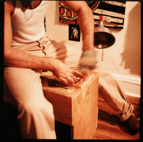 A photograph of artist Adrian Kellard carving a wood block in his studio.