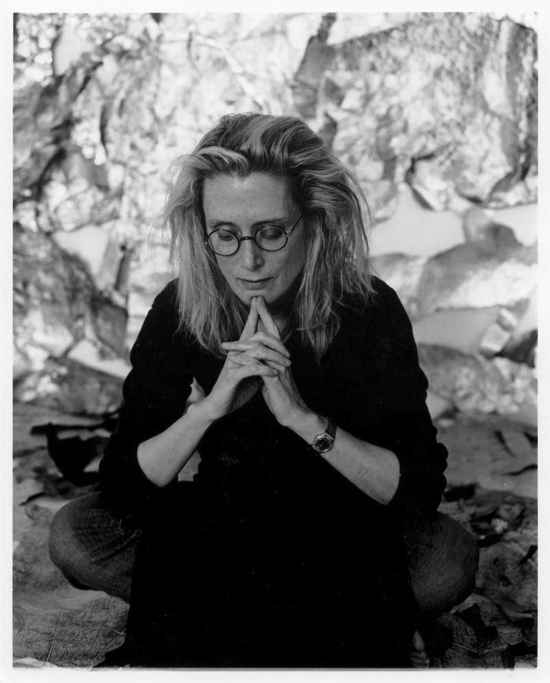 Artist Lesley Dill sits with her chin resting on her steepled index fingers, in a contemplative pose