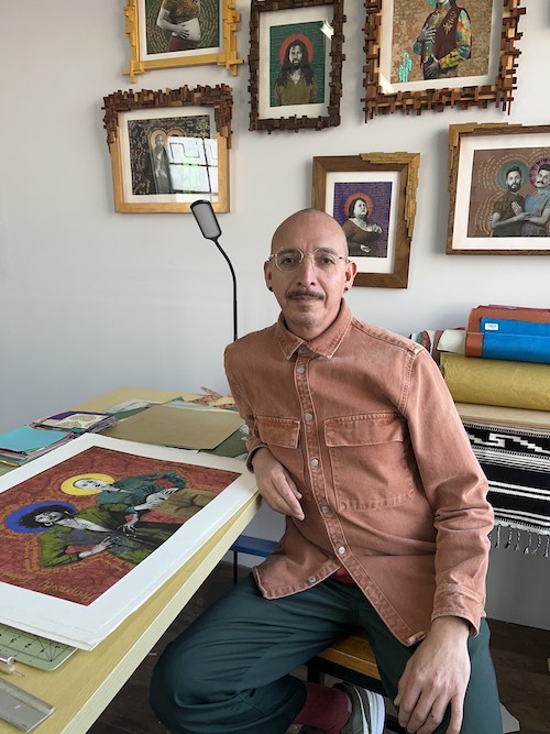 Artist Gabriel Garcia Roman sits in his studio, surrounded by examples of his portrait work