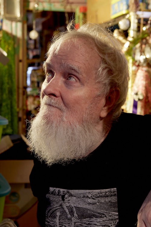 A close-up photo of artist Thomas Lanigan-Schmidt, who stands in his studio gazing up to the left