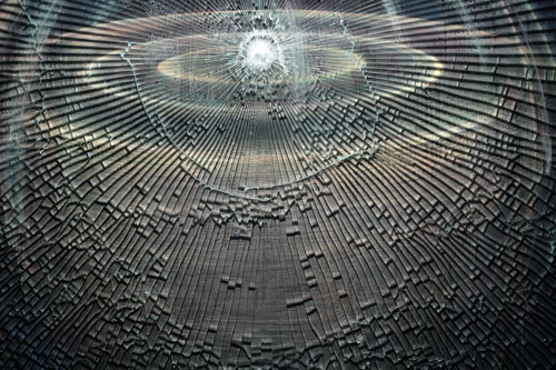A detail of the artwork by Donald Grant titled Vessel, showing the point of impact on the tempered glass covering the painting, from which radiate all the cracks in the glass.
