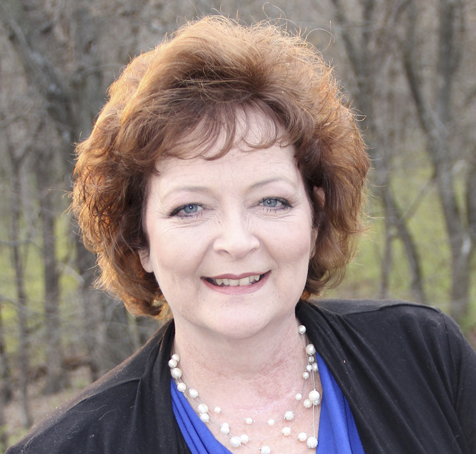 A photo of Karen Moore outside on a bright sunny day. She smiles at the camera. 