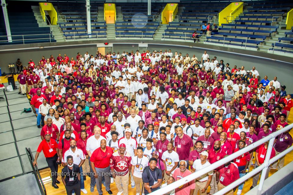 A group of men and boys pose for a photo in an auditorium.