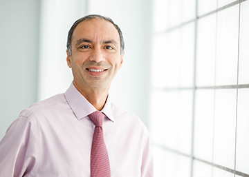 Sandeep Dhindsa, M.D., a professor of medicine and the director of SLU’s Division of Endocrinology. Dr. Dhindsa wears a pastel pink button-down shirt with a red tie. He is photographed indoors near a window. 