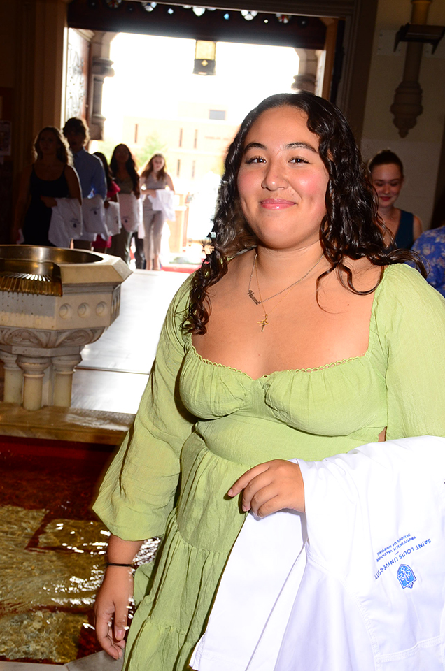 A nursing student poses with her white coat.