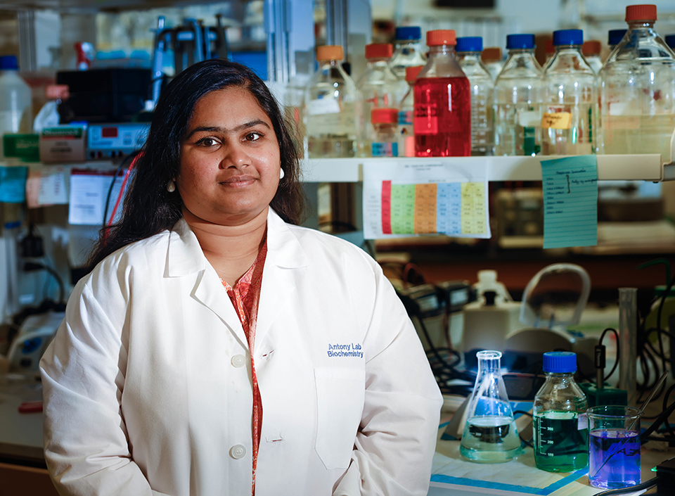 Sahiti Kuppa is shown here in a lab wearing a white lab coat. 