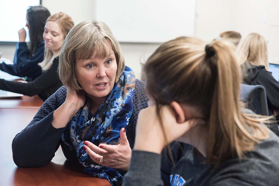 Kathryn Mitchell Pierce speaks with a student in a classroom.
