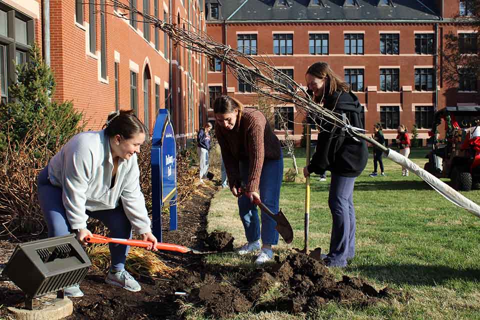 From left Tessa Bellante, Delaney Walker, and Maggie Schreiber work to dig a hole for a new tree outside of DuBourg Hall on Friday, Dec. 9, 2022. Photo by Joe Barker. 