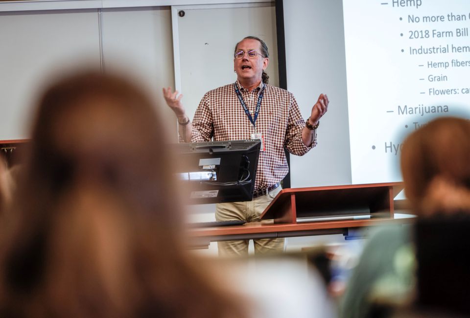 a man standing in front of a crowd delivers a lecture 