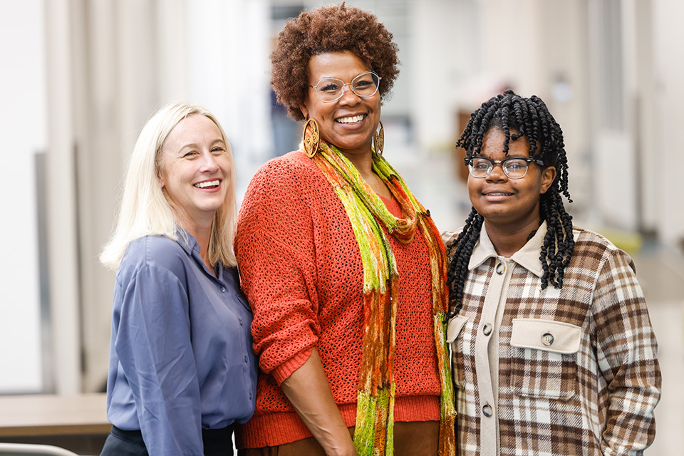 A photo of three people smiling for the camera.