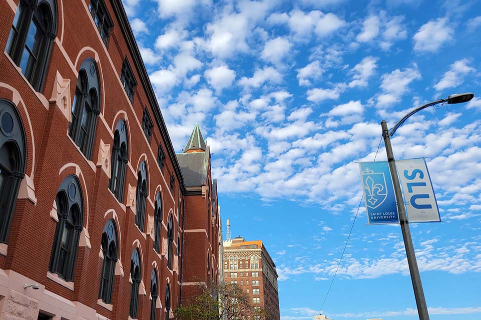 A photo of DuBourg Hall with on a bright and sunny day with some clouds in the sky. 