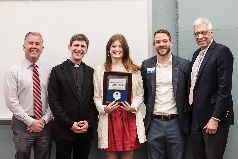 Saint Louis University's Gabby Chiodo has been named a 2023 Truman Scholar. Chiodo is one of 62 Truman Scholars selected this year. She was surprised with the annoucement on Tuesday, April 11. From left are Provost Mike Lewis, Ph.D.;  Catholic Studies Academic Program Director Fr. Matthew Baugh, S.J.; Chiodo; Honors Program Director Robert Pampel, Ph.D.; and President Fred P. Pestello, Ph.D. Photo by Sarah Conroy.

