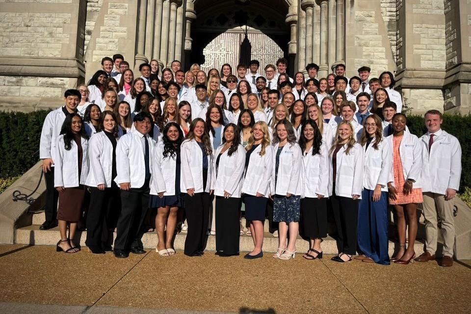 SLU PT students line up outside St. Francis Xavier College Church in their white coats.