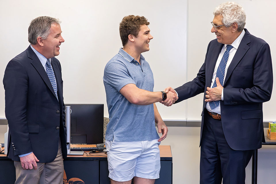 Sam Aitchison, center, shakes hands with President Fred P. Pestello, Ph.D., right. Provost Mike Lewis, Ph.D., left, is also pictured.