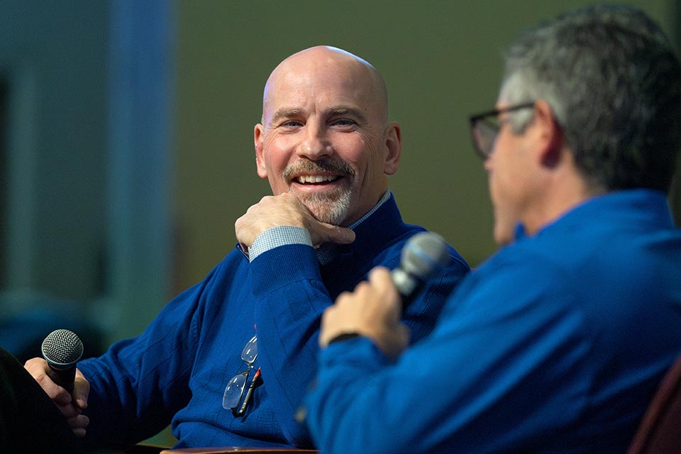 a man in blue shirt smiling at another man