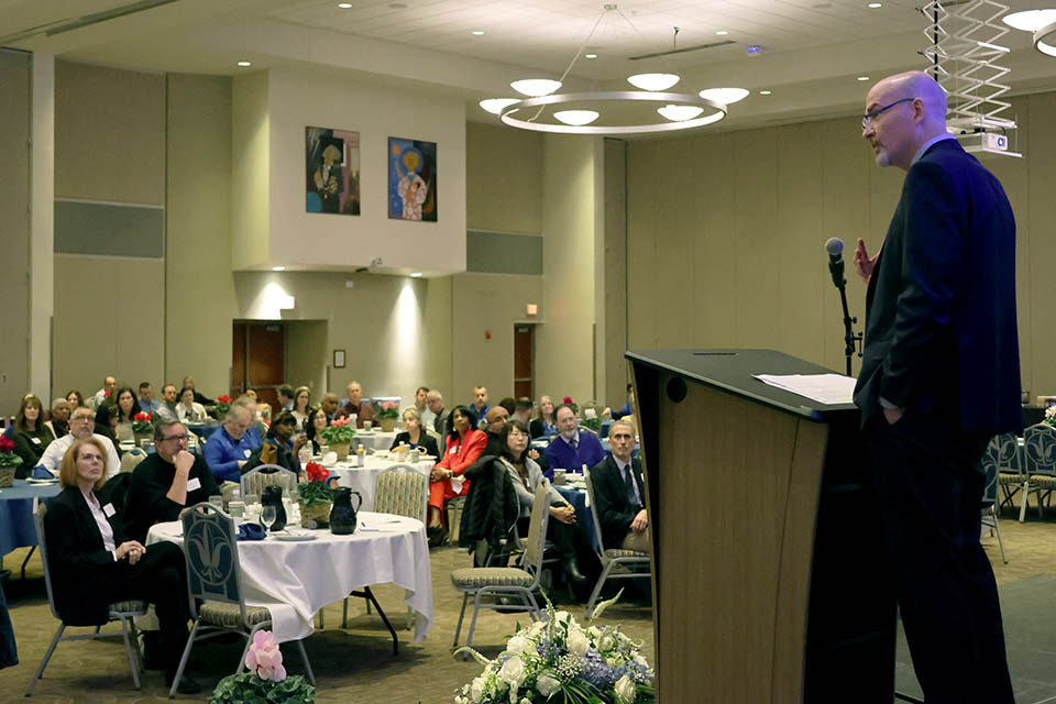 a man standing at a podium with a microphone in front of a crowd of people