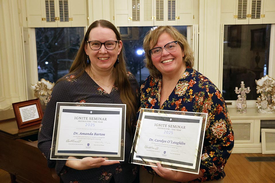 two women pose holding awards