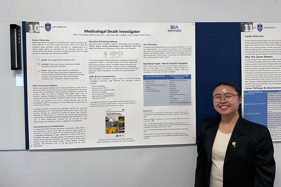 a student smiles in front of a poster