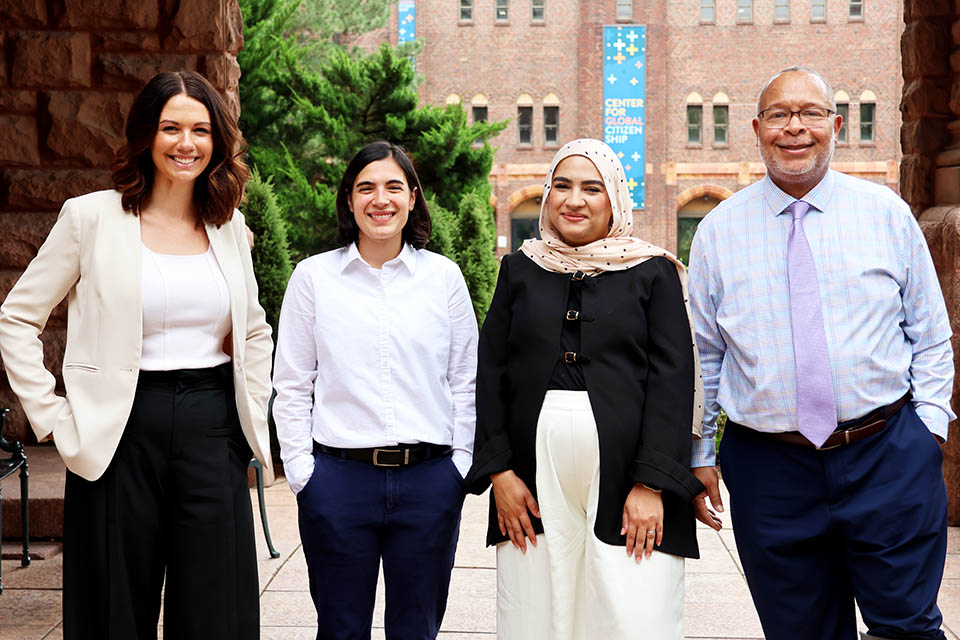 Four people posing for a photo outside