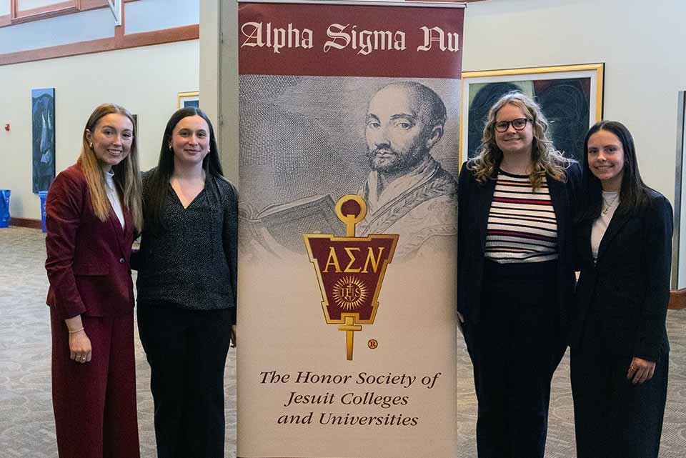 four women stand in front of a sign