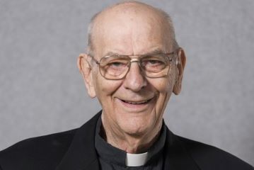 A headshot of Father John A. Apel, S.J. He smiles at the camera.