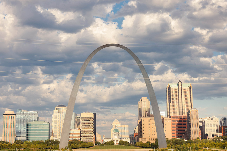 Ariel photo of the St. Louis Arch on a sunny day with skyscrapers behind it.