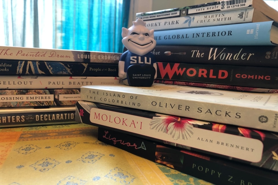 The Billiken sits atop a stack of books.