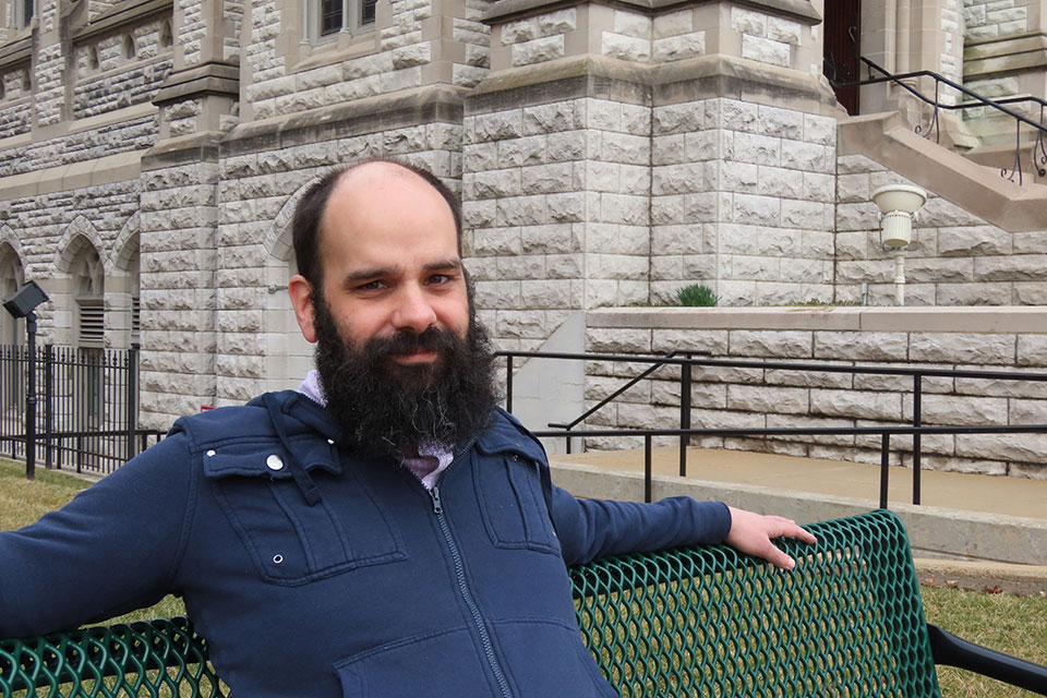 Harold Brasewell, Ph.D., sits on a bench near St. Francis Xavier College Church on the campus of Saint Louis University.