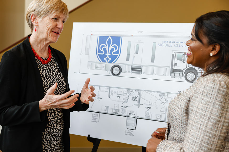 A photo of School of Medicine Dean Christine Jacobs, M.D., showing Congresswoman Cori Bush design plans for a mobile health clinic.