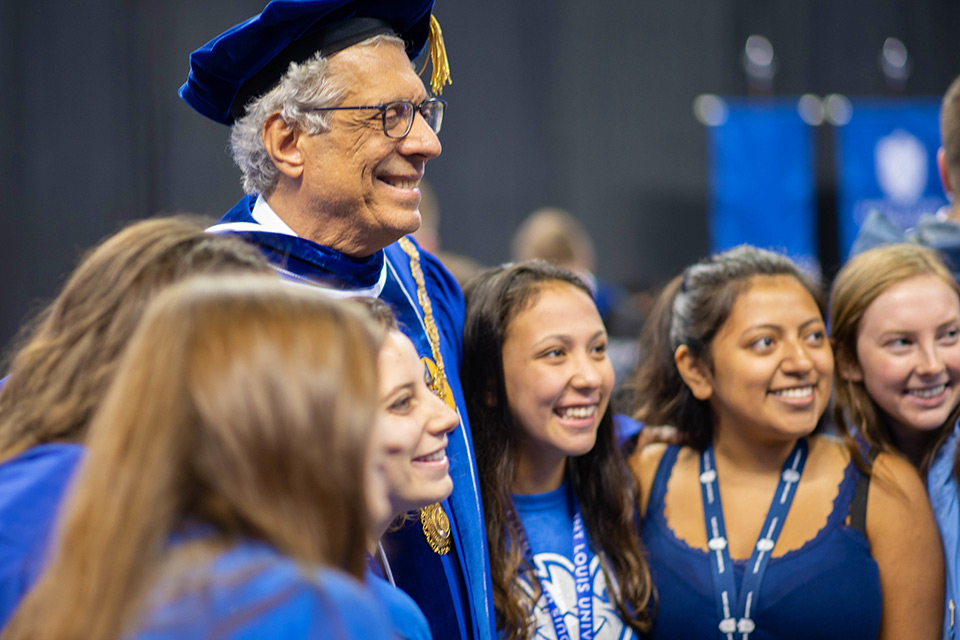 A photo of Dr. Pestello with students at a commencement ceremony.