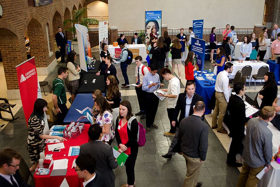 Job fair attendees walk between tables and booths.