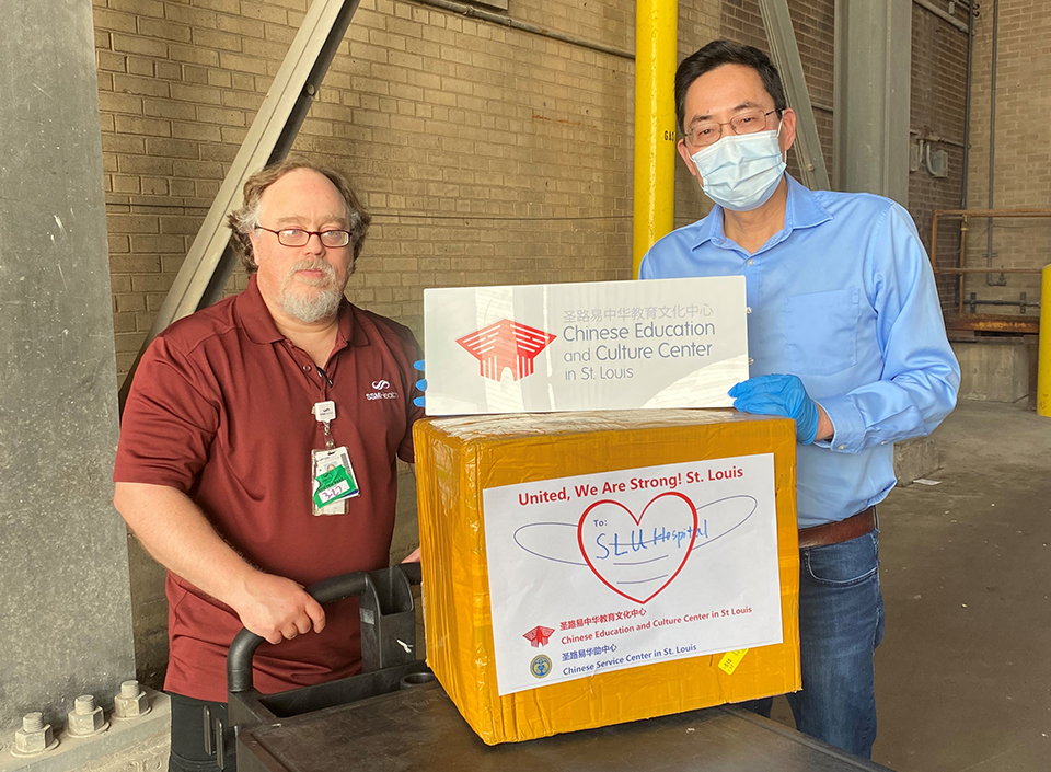 A staff member from SSM Health Saint Louis University Hospital (left) accepts donated PPEs from a volunteer with the "United! We are Strong St. Louis" campaign.