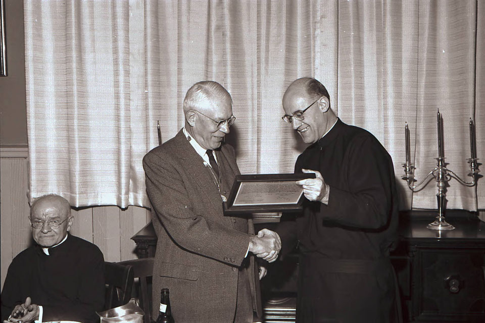 SLU research Edward Doisy, Ph.D. (second from left) shows his Nobel Prize to University President Patrick Holloran, S.J. (right) as Alphonse Schwitalla, S.J., looks on (far left).