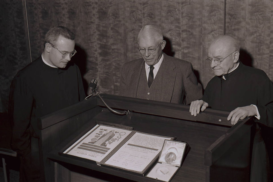 Alphonse Schwitalla, S.J. (right) joins Edward Doisy, Ph.D. (center) in viewing Doisy's Nobel Prize diploma and medal.
