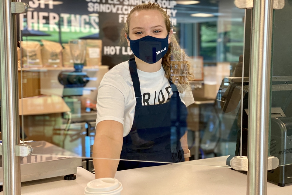 Student Olivia McQuilkin serves coffee at Fresh Gatherings in a mask.