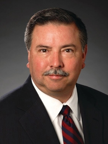 A photo of late trustee George Paz looking at the camera and wearing a blazer and tie.