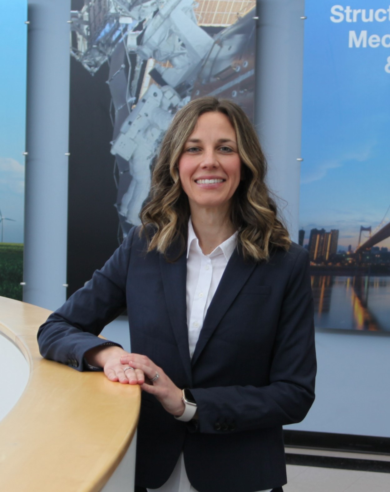 Dr. Jenna Gorlewicz smiles at the camera. She rests her arm on a wall. 