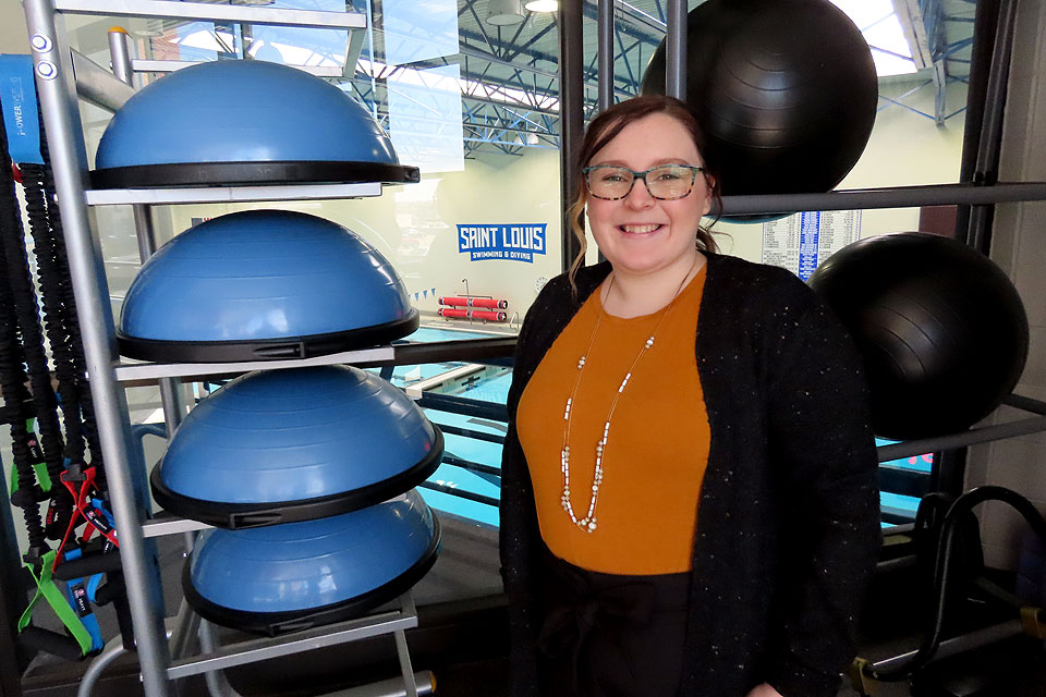 Tori Harwood in the Simon Recreation Center overlooking SLU's pool with exercise equipment behind her.
