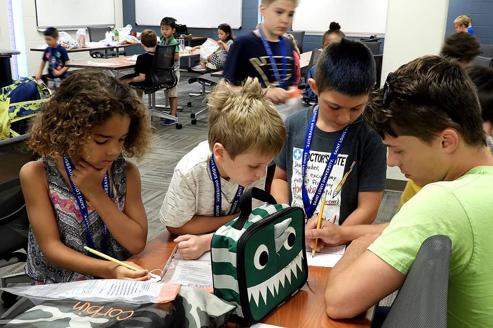 Campers participating in Summer at SLU's "Mad Science" camp work out a forensics problem with a camp counselor.