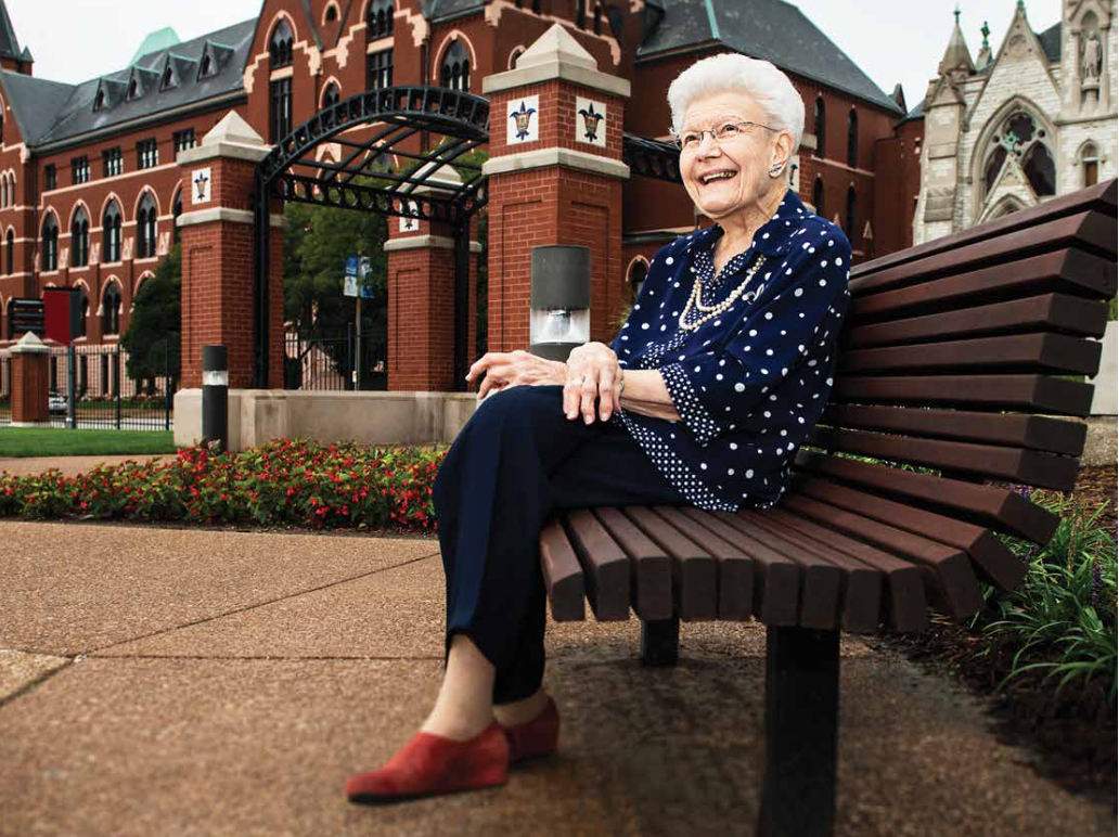 Dame Mary Bruemmer sits near a SLU fountain at the corner of Grand and Lindell Boulevards. DuBourg Hall is in the background.