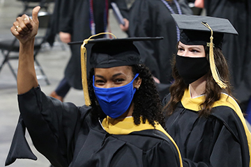 A new SLU graduate gives a thumbs-up during College for Public Health and Social Justice precommencement ceremony in Chaifetz Arena. 