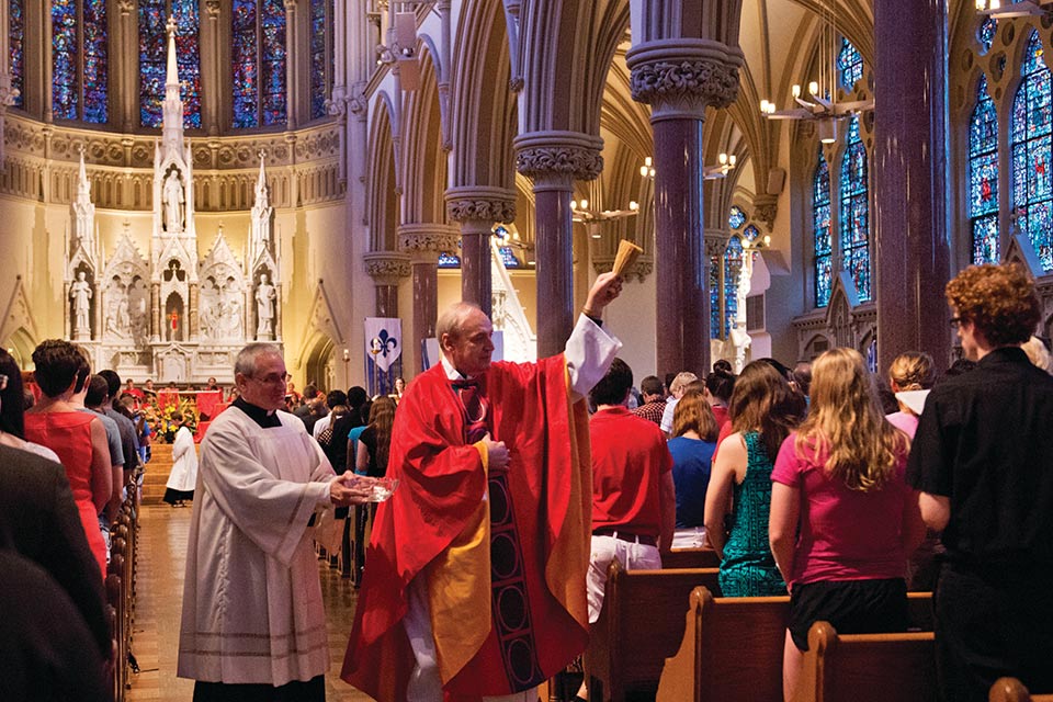 A photo of Father Paul Stark, S.J., blessing worshippers at St. Francis Xavier College Church in 2013