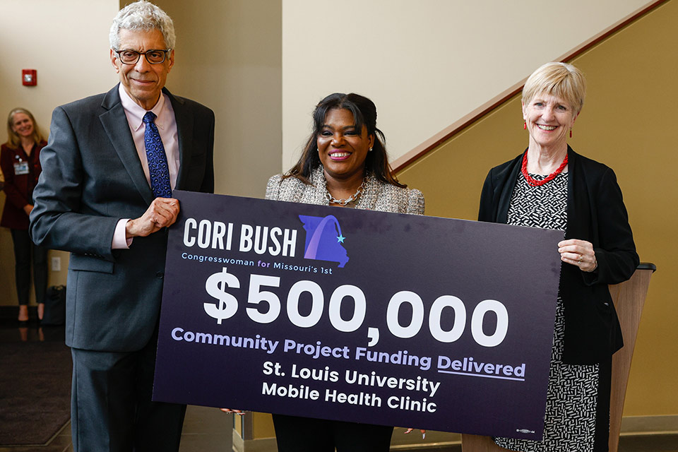SLU President Fred P. Pestello, Ph.D.; Congresswoman Cori Bush; and School of Medicine Dean Christine Jacobs, M.D. with the $500,000 check for funding Bush secured for the University to purchase a mobile health clinic. Photo by Sarah Conroy.