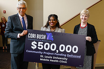 A photo of SLU President Fred P. Pestello, Ph.D.; Congresswoman Cori Bush; and School of Medicine Dean Christine Jacobs, M.D. with the $500,000 check for funding Bush secured for the University to purchase a mobile health clinic.
