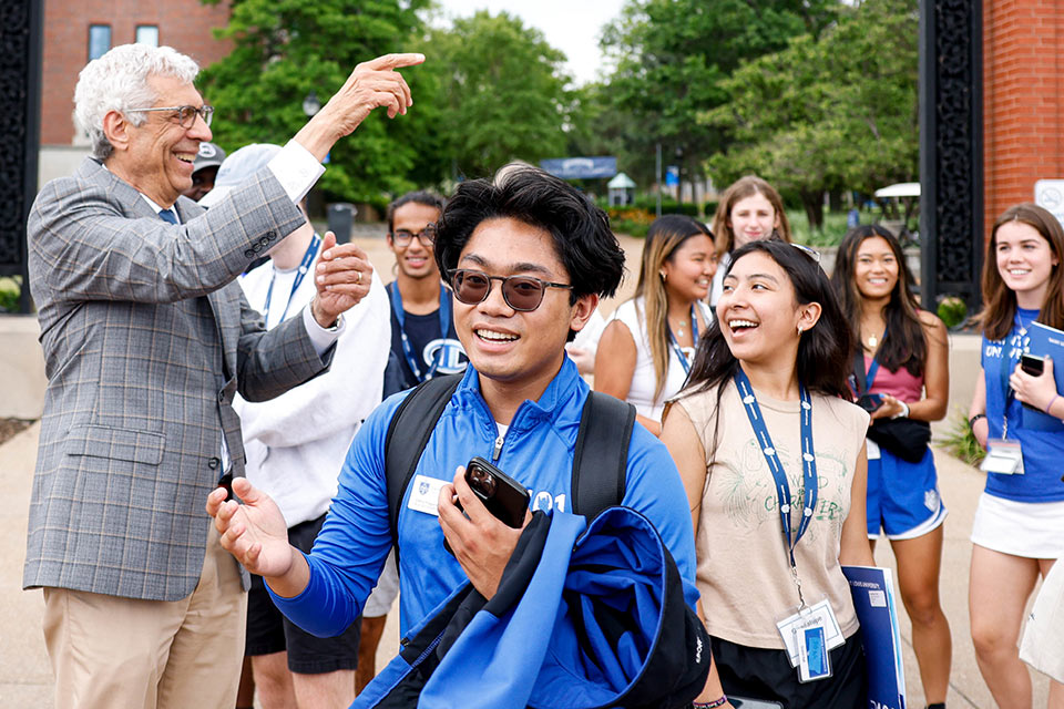A photo of University President Fred P. Pestello, Ph.D., greeting smiling SLU 101 students during the second day of the two-day new student orientation outside on campus on June 24, 2022.