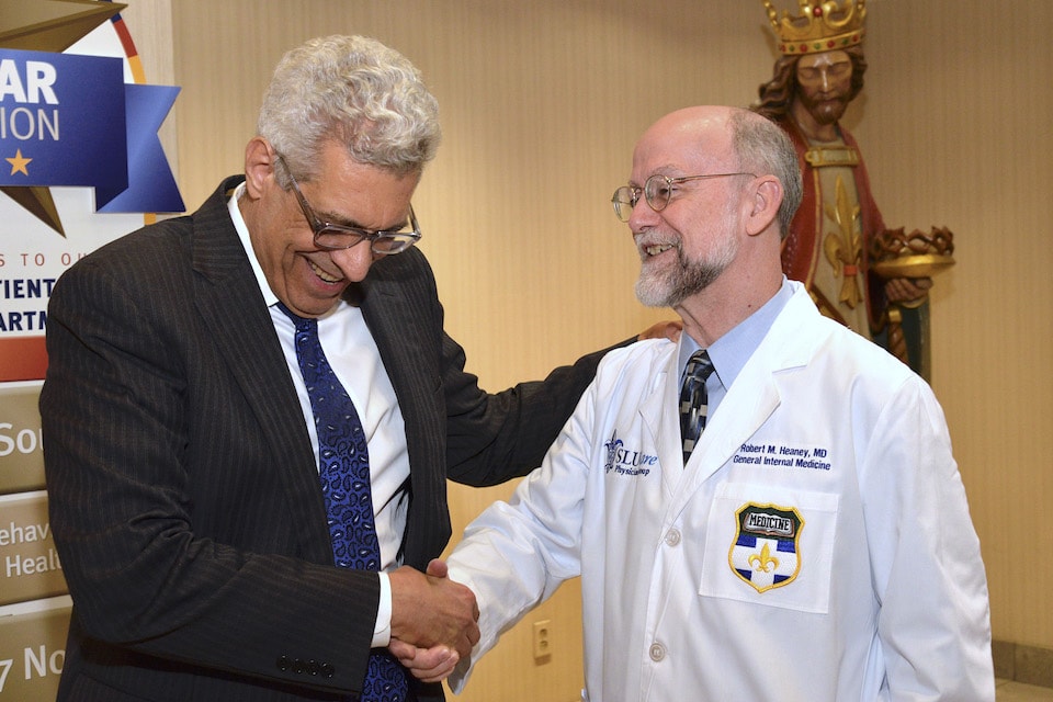   University President Fred P. Pestello, Ph.D., shakes hands with Robert Heany, M.D., SLUCare's chief medical officer. Photo by Kevin Lowder 