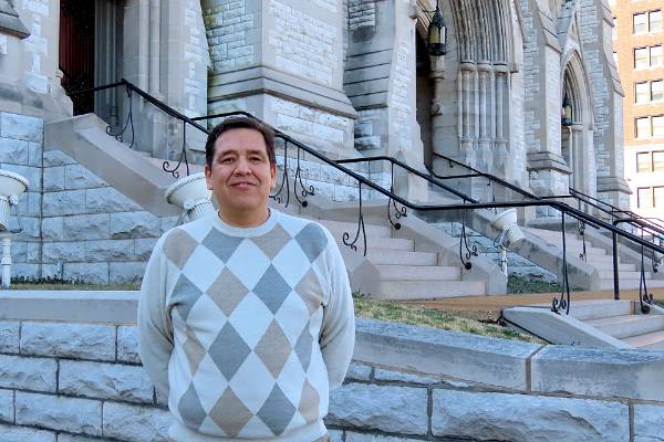SLU sociologist Ness Sandoval, Ph.D., stands on the steps of St. Francis Xavier College Church.