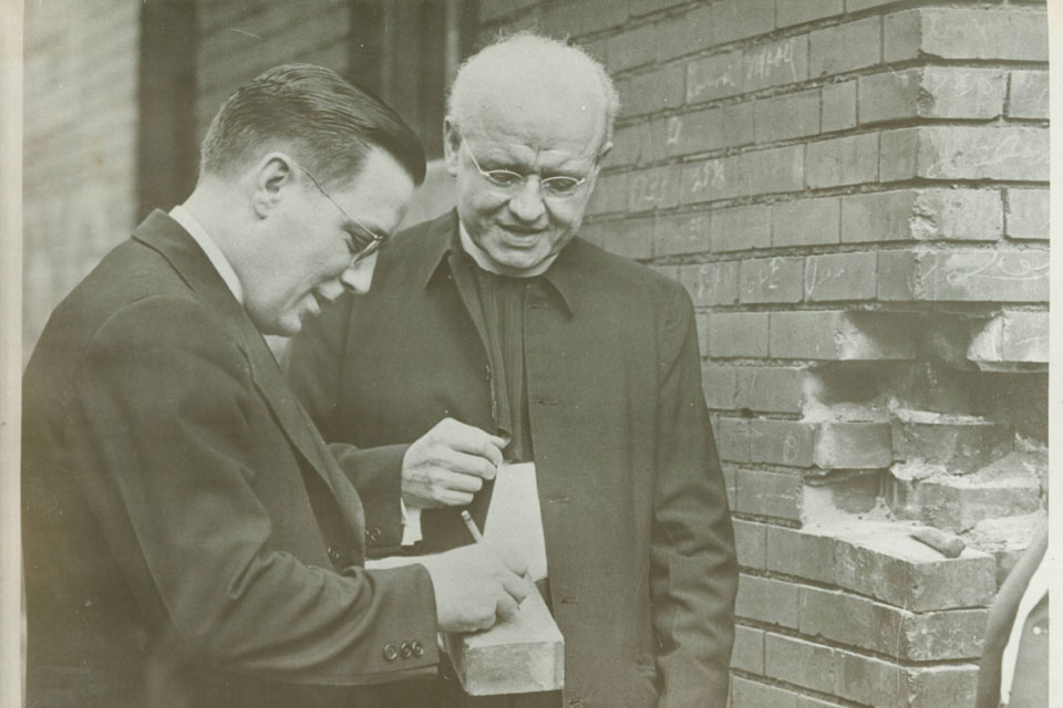 University President Patrick Holloran, S.J., signs a brick before Dean Alphonse Schwitalla, S.J., as the pair await the construction of Schwitalla Hall.
